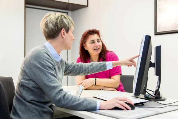 Zwei Frauen sehen auf einen Computer Zwei Frauen sehen auf einen Computer
