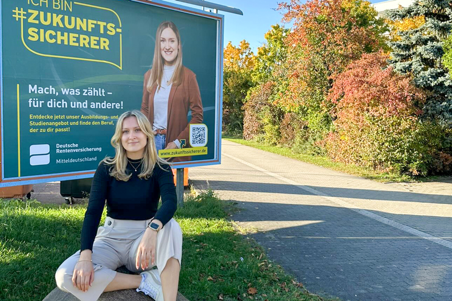 Eine junge Frau vor einem großen Plakat, auf dem sie zu sehen ist Eine junge Frau vor einem großen Plakat, auf dem sie zu sehen ist