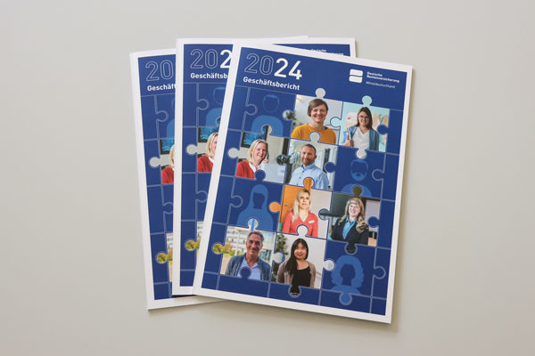 Drei Ausgaben des Geschäftsberichts 2024 liegen im aufgefächert auf einem grauen Untergrund. Drei Ausgaben des Geschäftsberichts 2024 liegen im aufgefächert auf einem grauen Untergrund.