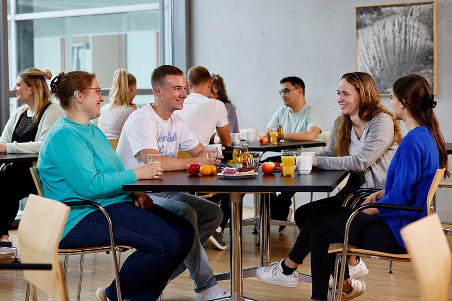 Eine Gruppe von jungen Leuten sitzt zum Frühstück zusammen in der Cafeteria Eine Gruppe von jungen Leuten sitzt zum Frühstück zusammen in der Cafeteria