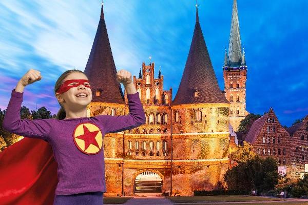 Ein Mädchen im Superheldenkostüm steht vor dem Lübecker Holsten-Tor.