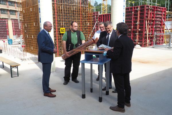 Fünf Männer befüllen die Zeitkapsel, die im Boden des Neubaus versenkt wird. Fünf Männer befüllen die Zeitkapsel, die im Boden des Neubaus versenkt wird.