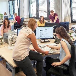 Foto: Nachwuchskräfte bei ihrer praktischen Ausbildung in einem Großraumbüro.