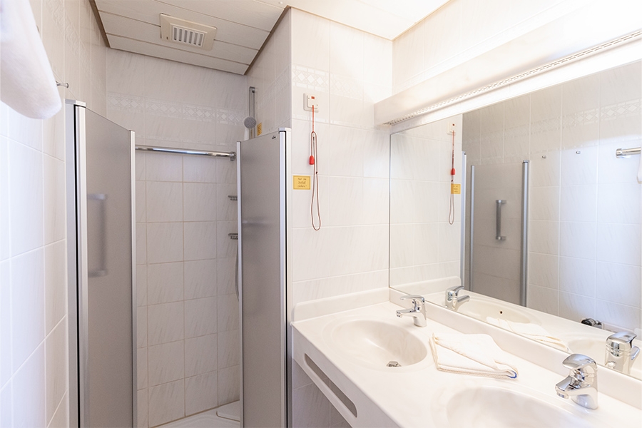 Ein beispielhaftes Badezimmer für Patienten mit Dusche, Spiegel und Waschtisch. Ein beispielhaftes Badezimmer für Patienten mit Dusche, Spiegel und Waschtisch.