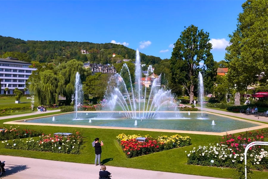 Ein Wasserbecken mit Fontänen umgeben von Wiese und Blumen im Kurpark Bad Kissingen. Ein Wasserbecken mit Fontänen umgeben von Wiese und Blumen im Kurpark Bad Kissingen.