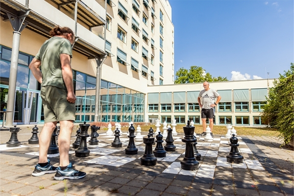 Zwei Patienten spielen auf dem großen Außenschachbrett. Zwei Patienten spielen auf dem großen Außenschachbrett.
