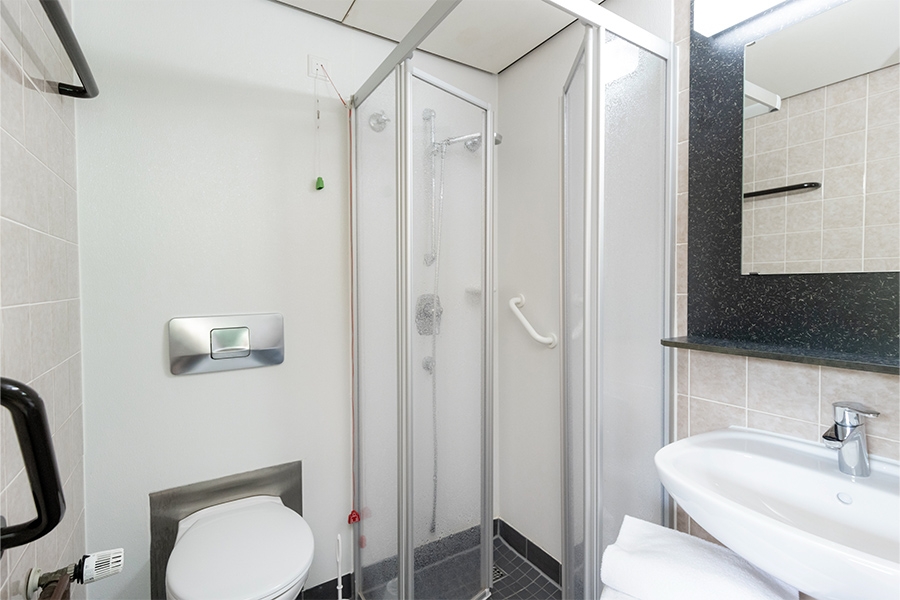 Ein beispielhaftes Badezimmer mit Toilette, Dusche, Waschbecken und Spiegel. Ein beispielhaftes Badezimmer mit Toilette, Dusche, Waschbecken und Spiegel.