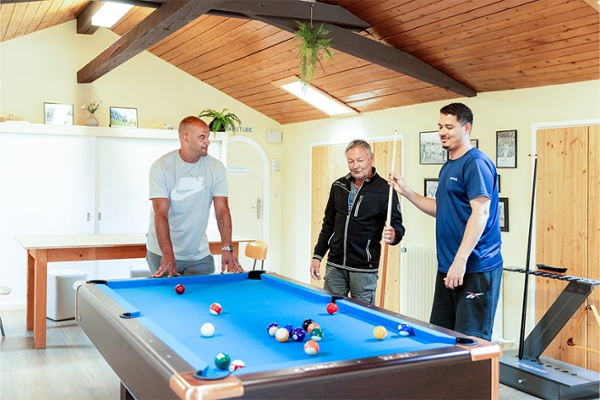 Drei Patienten spielen im Aufenthaltsraum Billard. Drei Patienten spielen im Aufenthaltsraum Billard.