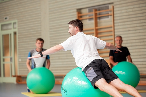 Patienten trainieren in der Sporthalle auf Gymnastikbällen. Patienten trainieren in der Sporthalle auf Gymnastikbällen.