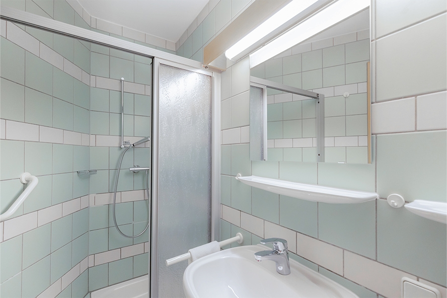 Ein beispielhaftes Badezimmer mit Dusche, Waschbecken und Spiegel. Ein beispielhaftes Badezimmer mit Dusche, Waschbecken und Spiegel.