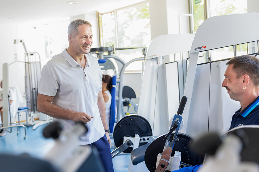 Ein Therapeut unterstützt einen Patienten beim Training mit einem Trainingsgerät. Ein Therapeut unterstützt einen Patienten beim Training mit einem Trainingsgerät.