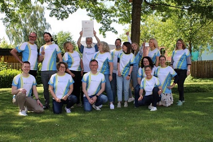 Mitarbeiter der DRV Oldenburg-Bremen in einheitlichen T-Shirts halten ein Zertifikat in den Händen hoch. 