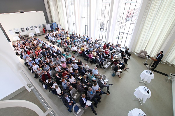 Auf Stuhlreihen sitzen die zahlreichen Besucher der Veranstaltung und hören den Redebeiträgen zu. Auf Stuhlreihen sitzen die zahlreichen Besucher der Veranstaltung und hören den Redebeiträgen zu.