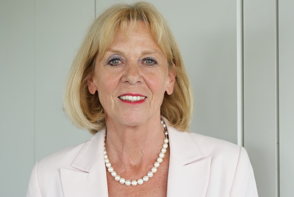 Eine Frau in einer hellrosa Jacke und einer Perlenkette blickt lächelnd in die Kamera Eine Frau in einer hellrosa Jacke und einer Perlenkette blickt lächelnd in die Kamera