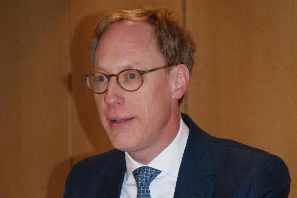 Mann mitteleren Alters im Anzug spricht zur Vertreterversammlung Mann mitteleren Alters im Anzug spricht zur Vertreterversammlung