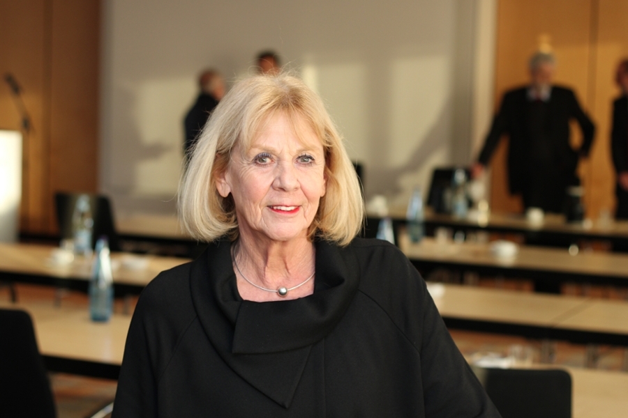 Eine Frau in einem Sitzungssaal blickt lächelnd in die Kamera Eine Frau in einem Sitzungssaal blickt lächelnd in die Kamera