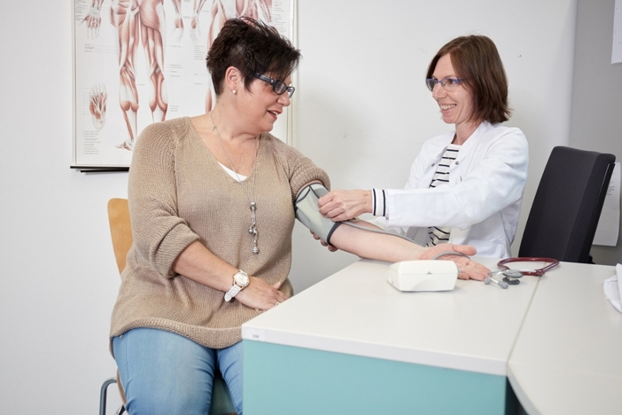 Eine Mitarbeiterin untersucht den Blutdruck einer Patienten. Eine Mitarbeiterin untersucht den Blutdruck einer Patienten.