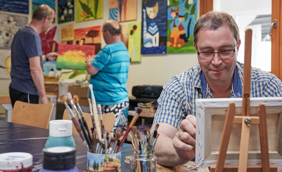 Mann sitzt vor einer Staffelei Mann sitzt vor einer Staffelei