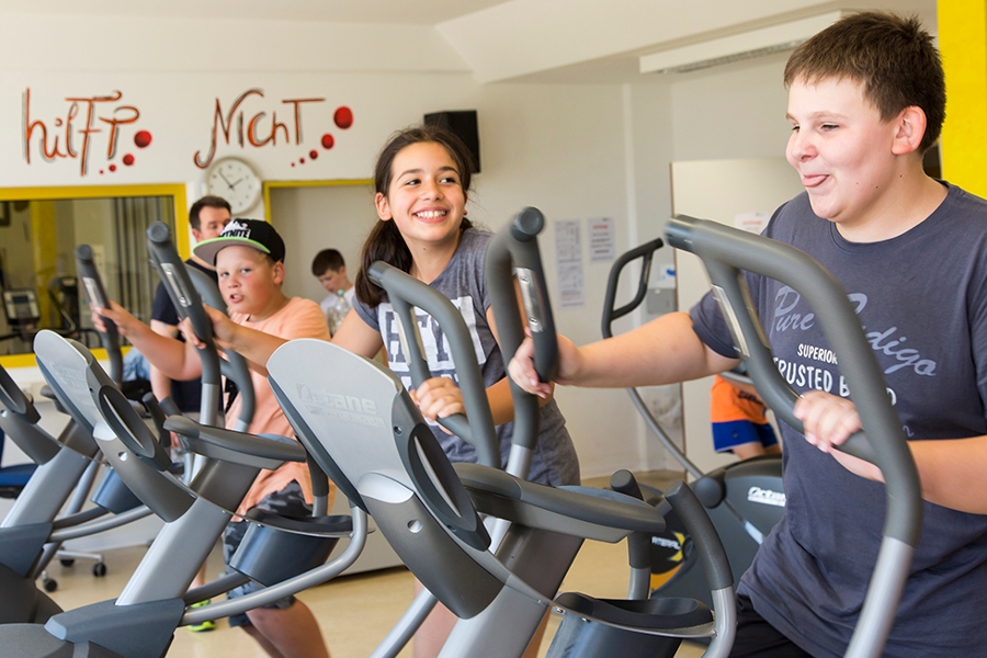 Drei Kinder trainieren auf Ergometern. Drei Kinder trainieren auf Ergometern.