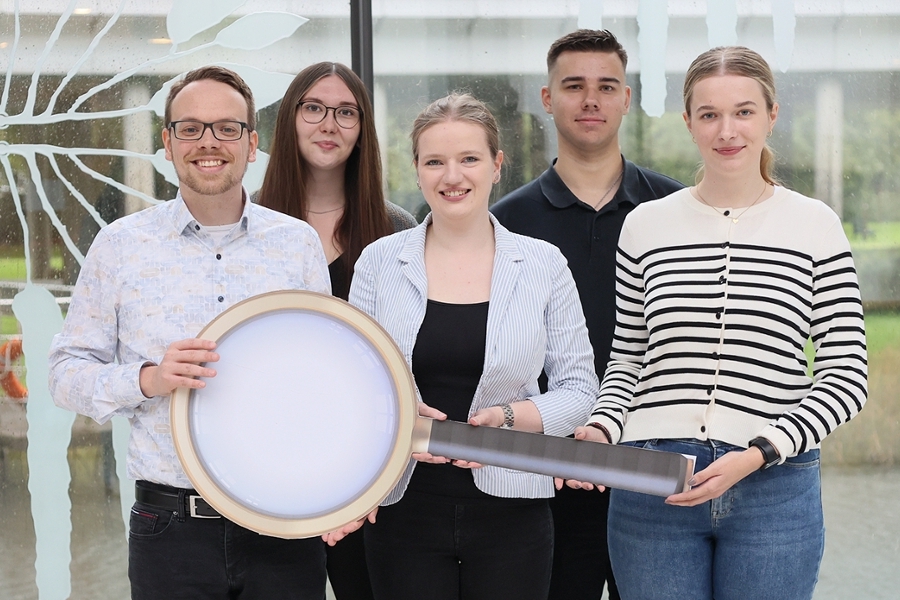 Eine Gruppe junger Leute halten zusammen eine übergroße Lupe. Eine Gruppe junger Leute halten zusammen eine übergroße Lupe.