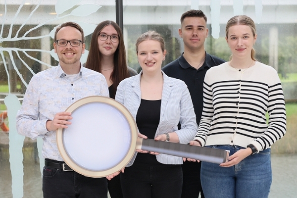 Eine Gruppe junger Leute halten zusammen eine übergroße Lupe. Eine Gruppe junger Leute halten zusammen eine übergroße Lupe.