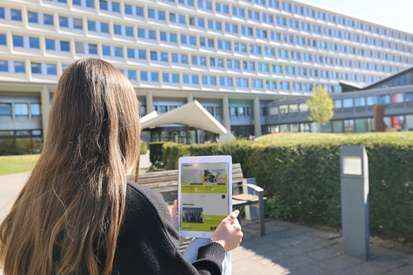 Frau sitzt mit Tablet vor einem Gebäude. Frau sitzt mit Tablet vor einem Gebäude.