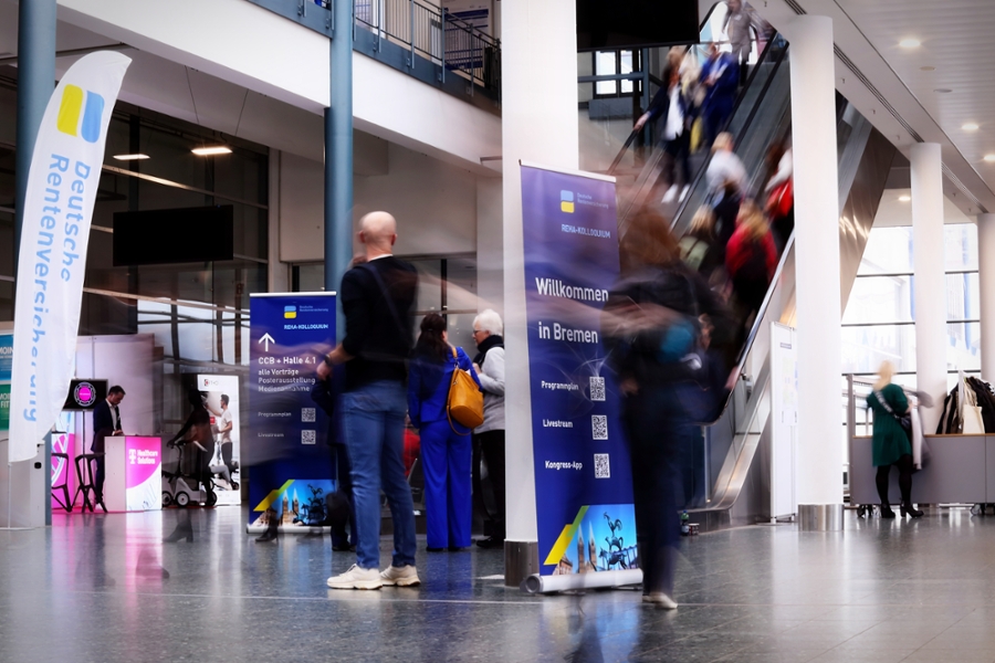 Menschen in einer Halle mit verschiedenen Info-Aufstellern Menschen in einer Halle mit verschiedenen Info-Aufstellern
