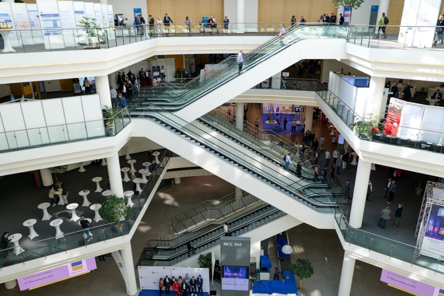 Blick in eine Messehalle mit Menschen auf Rolltreppen. Blick in eine Messehalle mit Menschen auf Rolltreppen.