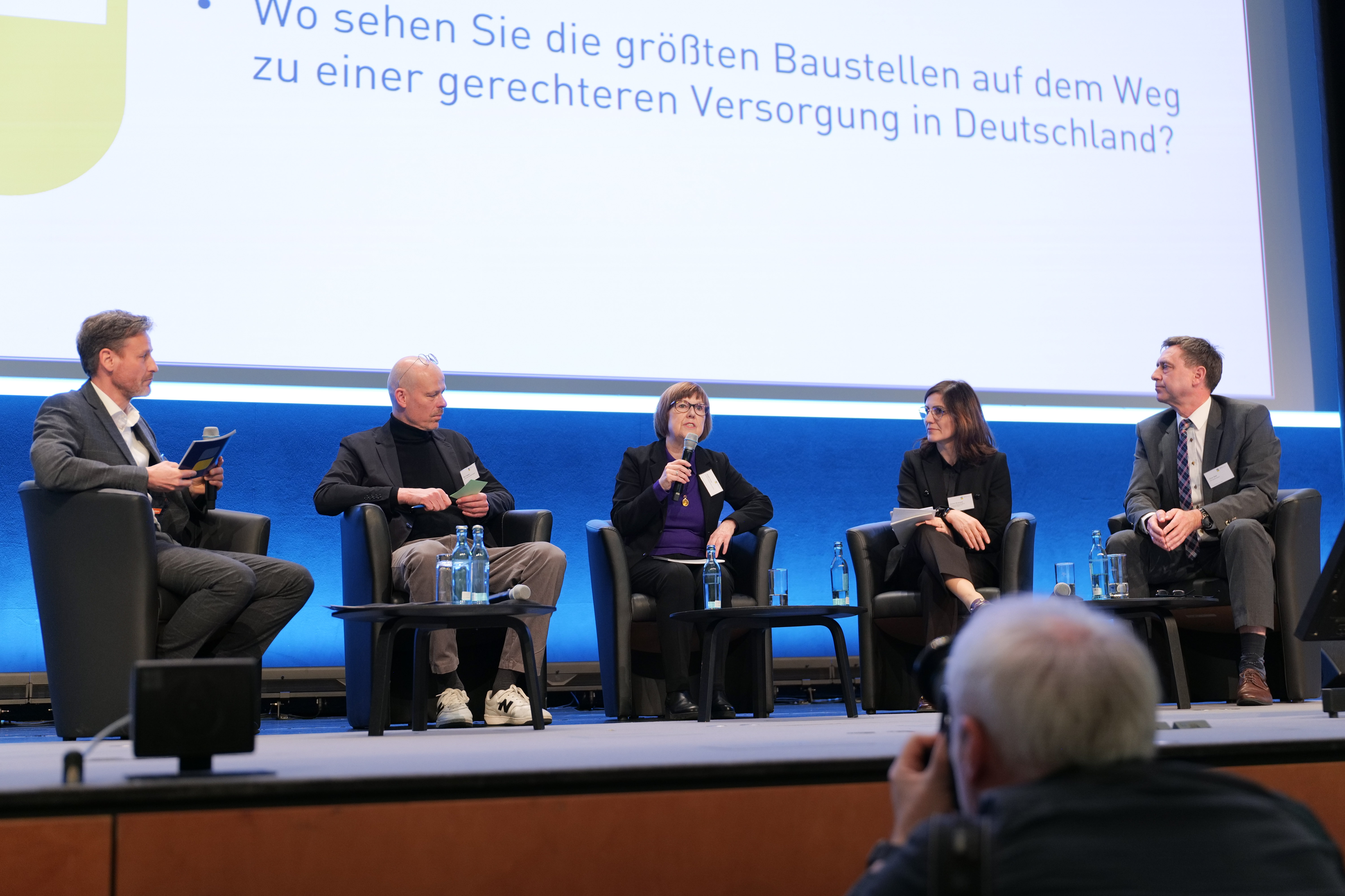 Ein Saal mit einer Podiumsdiskussion Ein Saal mit einer Podiumsdiskussion