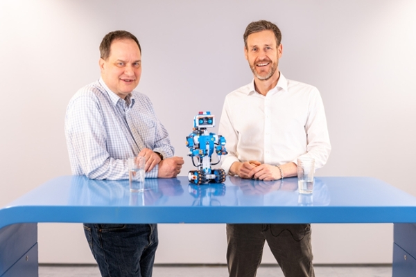 Zwei Männer stehen an einem Tisch mit einem Roboter. Zwei Männer stehen an einem Tisch mit einem Roboter.