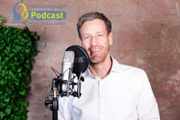 Mann vor großem Mikrofon, steht vor einer Mauer Mann vor großem Mikrofon, steht vor einer Mauer